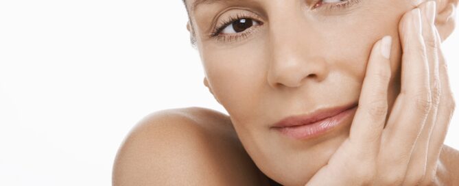 Woman smiling and touching her smooth facial skin